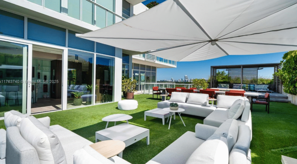 Luxury rooftop terrace at Ritz-Carlton Residences Miami Beach featuring modern white outdoor furniture, artificial grass, umbrellas, and city skyline views